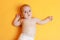 Serious baby boy lying on her back on yellow orange sheet