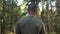 Serious bald and bearded man on the background of the forest with his back in the frame. Portrait of a lumberjack