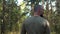 Serious bald and bearded man on the background of the forest with his back in the frame. Portrait of a lumberjack