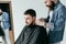 serious barber shaving client hair at barbershop