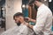 Serious bearded guy doing haircut in barbershop. barbershop concept