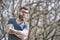 Serious bearded man standing with his arms crossed. Handsome man with tattoo wearing trendy sunglasses posing outdoors