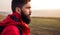 Serious bearded traveler standing in field