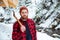 Serious bearded young lumberjack with axe at mountains in winter