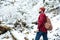 Serious bearded young man with backpack walking in winter forest