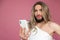 Serious beautiful transgender wearing blonde wig holding mobile phone, checking social networks