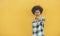 Serious black girl pointing on camera near yellow wall