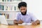 Serious black hipster businessman working at desk