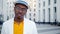 Serious black man in classic suit and glasses looks straight standing on grey paved street