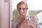 Serious Blond Woman with Glasses Holding a Cup