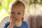 Serious blue-eyed infant kid eating cucumber