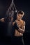 Serious boxer in gloves holding punching bag and looking at camera.