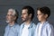 Serious boy, his father and grandpa standing together in row