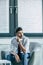 serious businessman sitting in armchair near window and looking away.