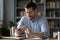 Serious businessman wearing spectacles using mobile phone sit at desk