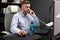 Serious Businessman working in office at computer Desk and talking on landline