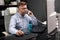 Serious Businessman working in office at computer Desk and talking on landline