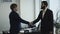 Serious businessmen in suit jackets shaking hands during office meeting. Partnership concept.