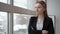 Serious businesswoman in black suit looking to window in modern office