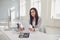 Serious busy businesswoman reads working documents sitting at a table with a computer