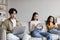 Serious busy japanese millennial mom, dad and teen daughter with personal devices sitting on sofa