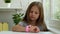 Serious caucasian little girl clicks on the screen of kids smartwatch. Sending messages by using smart watch. Concept of