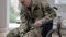 Serious Caucasian man in military uniform trying to stand up from wheelchair. Injured disabled middle aged soldier or