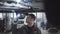 Serious Caucasian man in workwear and cap walking under car bottom with flashlight. Male adult auto mechanic examining