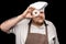 Serious chef in apron and hat looking through doughnut