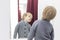 Serious Child - European blond boy tries on clothes in a store in the dressing room and looks at himself in the mirror