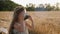 Serious child girl with long hair sits on a mown wheat field