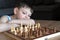 The serious child lost in thought playing chess. Playing board games, on coronavirus quarantine. The child playing chess