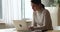 Serious concentrated female sit at table working on wireless laptop