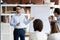 Serious confident business coach gives presentation on flipchart training workers