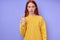 serious confident redhead woman in yellow stylish sweater demonstrating letter V