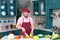 Serious cook in red apron and red bonnet at kitchen cuts vegetables