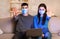 Serious couple in face mask gesturing stop sitting on couch