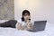 Serious and daydreaming asian beautiful girl work the laptop in the bed. Work from home concept