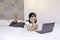 Serious and daydreaming asian beautiful girl work the laptop in the bed. Work from home concept