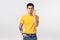 Serious and determined asian male model in yellow t-shirt, with tattoos, suck lips shut mouth, making zip gesture near