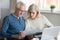 Serious elder husband and wife read bank documents at home
