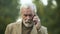 Serious elderly businessman talking on phone, bad news, communication technology
