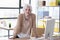 Serious elderly businesswoman stands leaning on wooden table