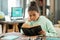 Serious elementary schoolgirl in casualwear reading book by table in living-room