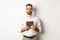 Serious employer working with digital tablet, reading in glasses, standing over white background