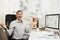 Serious and engrossed business man in shirt sitting at the desk, working at computer with modern monitor. Manager or worker.