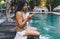 Serious ethnic woman surfing smartphone on poolside