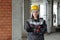 Serious female builder or engineer in workwear standing in unfinished building