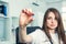 Serious Female doctor in white coat with stethoscope holding a pill between her fingers. Hand of a hospital medical expert shows t