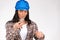 A serious female electrician examines a light bulb in a hard hat on a white background. Breaking gender stereotype